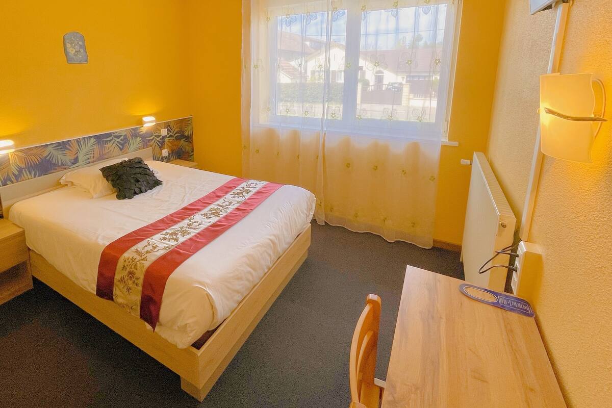 Una habitación de hotel con cama, mesita de noche y escritorio con silla.