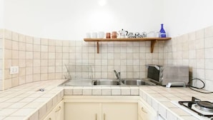 Eine Küche mit einem Gasherd, zwei Spülen, einem Toaster und einem Regal mit Küchenutensilien.