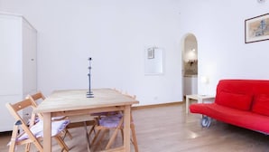 Ein Zimmer mit einem Holztisch, Stühlen, einem roten Sofa und einem gerahmten Bild an der Wand.