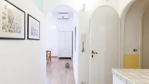 Ein Flur mit einer weißen Tür, einem kleinen Tisch und zwei gerahmten Bildern an der Wand.