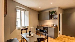 A compact kitchen with a dining area, a built-in stove, and a refrigerator. - Cappellari 4 Campo de Fiori (Rome)