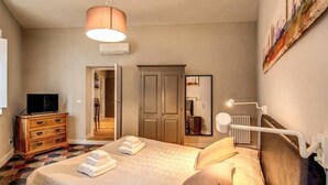 A bedroom with a bed, a dresser, a television, a wardrobe, and a painting on the wall. - Cappellari 4 Campo de Fiori (Rome)