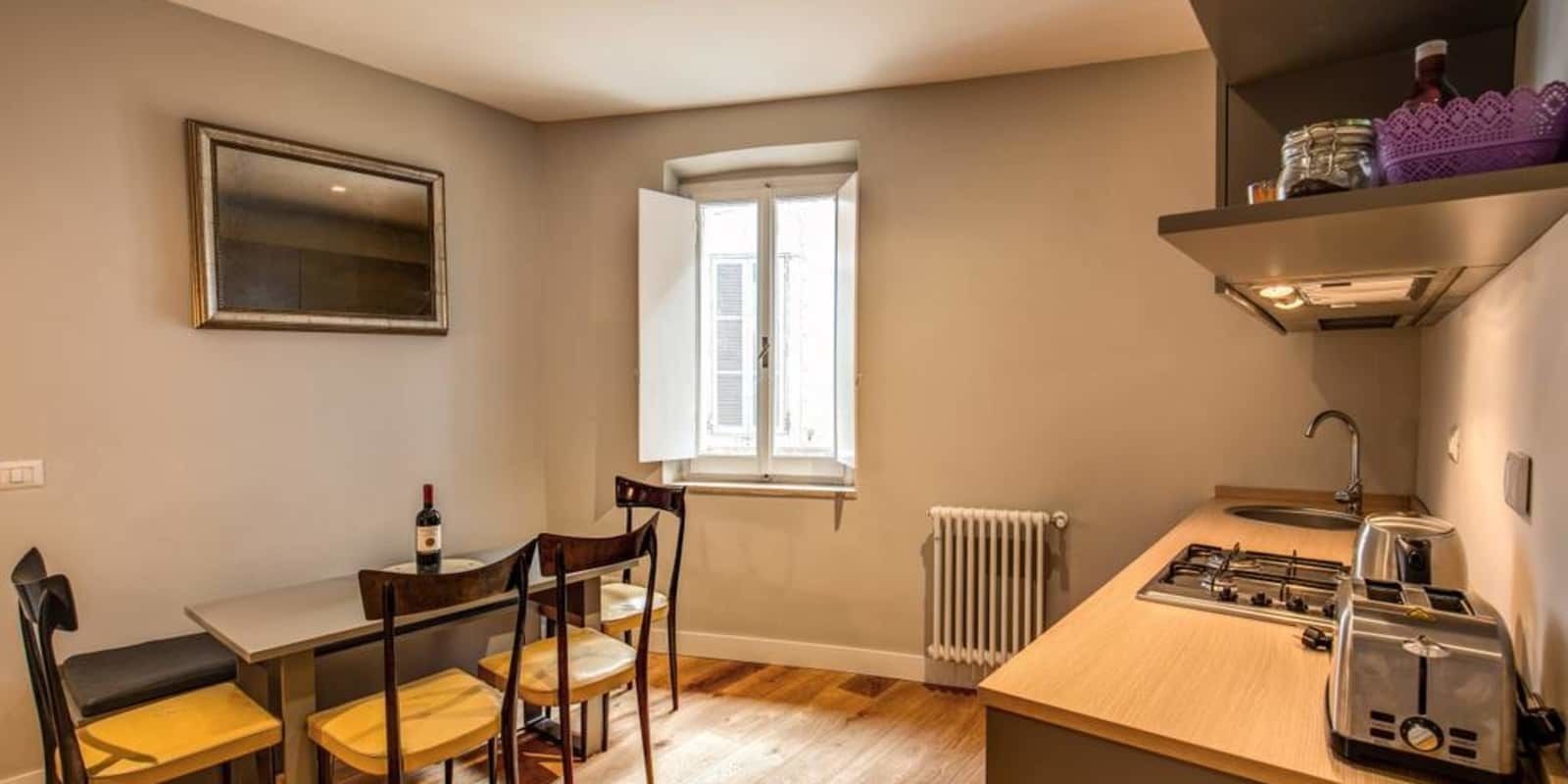 A compact kitchen with a window, a dining area with chairs, a table, and a stove.