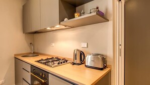 A compact kitchen with a gas stove, a toaster, and a kettle. - Cappellari 4 Campo de Fiori (Rome)