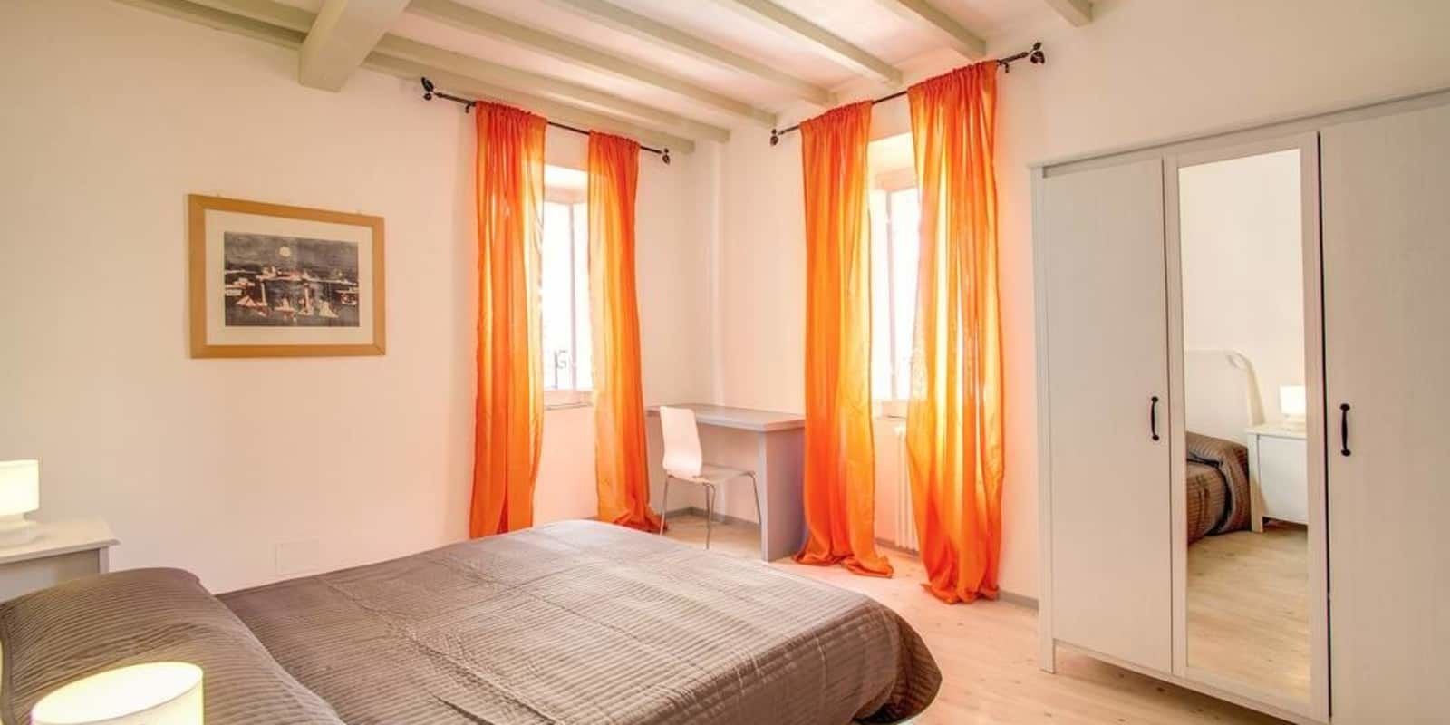 A bedroom with a bed, a desk, and a wardrobe.