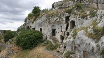 Una scogliera rocciosa con aperture simili a grotte e una scala che conduce verso l'alto.