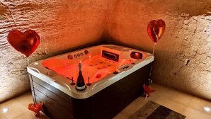 A hot tub in a corner with a rustic stone wall background. - B&B Duca Orsini (Gravina in Puglia)
