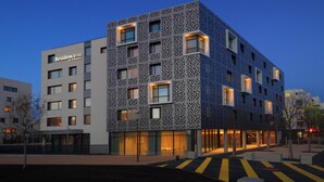 Un hôtel moderne doté d’une façade géométrique originale, de nombreuses fenêtres et d’une entrée bien éclairée.