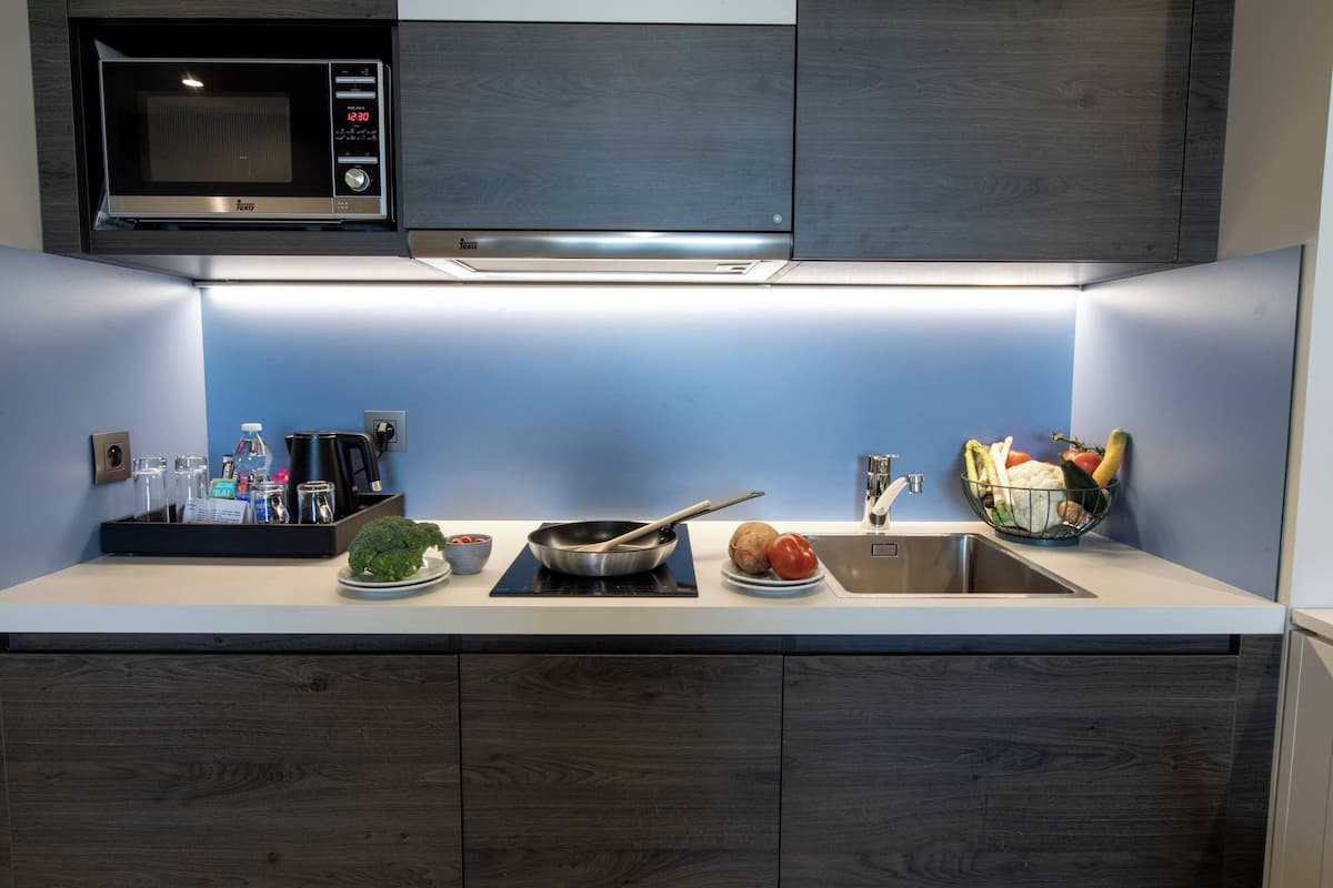 Une cuisine moderne équipée d’un four à micro-ondes, d’une cuisinière, d’un évier et d’un panier à fruits.