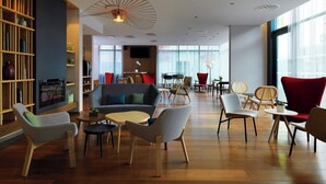 Un espace de détente moderne comprenant un canapé, des fauteuils, une table basse et une bibliothèque.