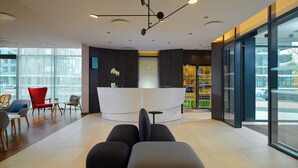 Un espace d’accueil moderne doté d’un comptoir central, d’un coin salon et offrant une vue dégagée grâce à de grandes fenêtres.