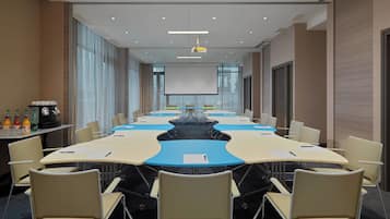 A conference room with a long table, chairs, a projector, and a screen.