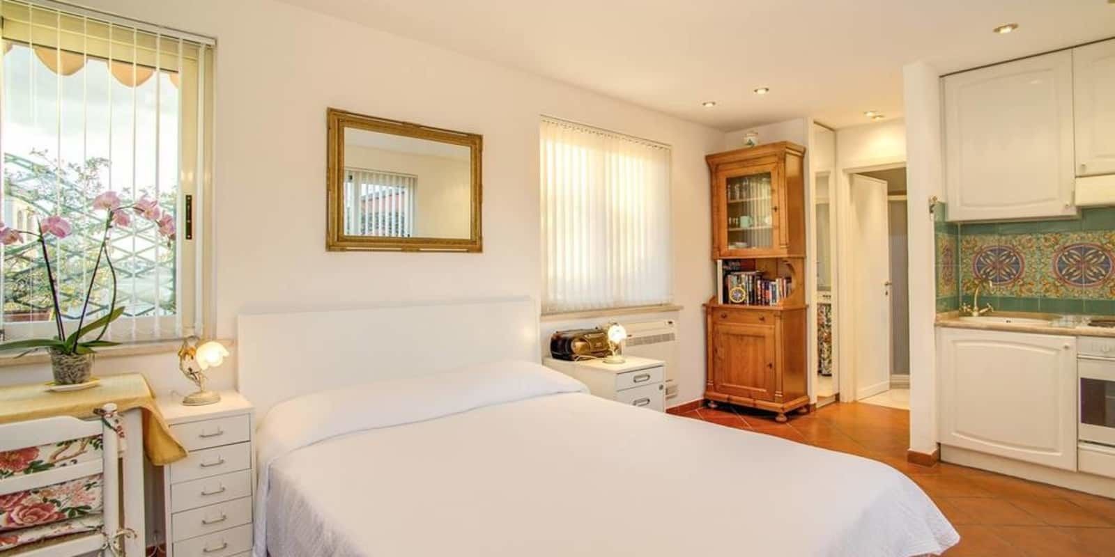 Un dormitorio con cama, mesita de noche, lámpara y ventana con persianas.