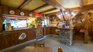 A rustic interior with wooden beams, a stone counter, and a variety of items on shelves. - Hotel Villa Plinia (Pragelato)