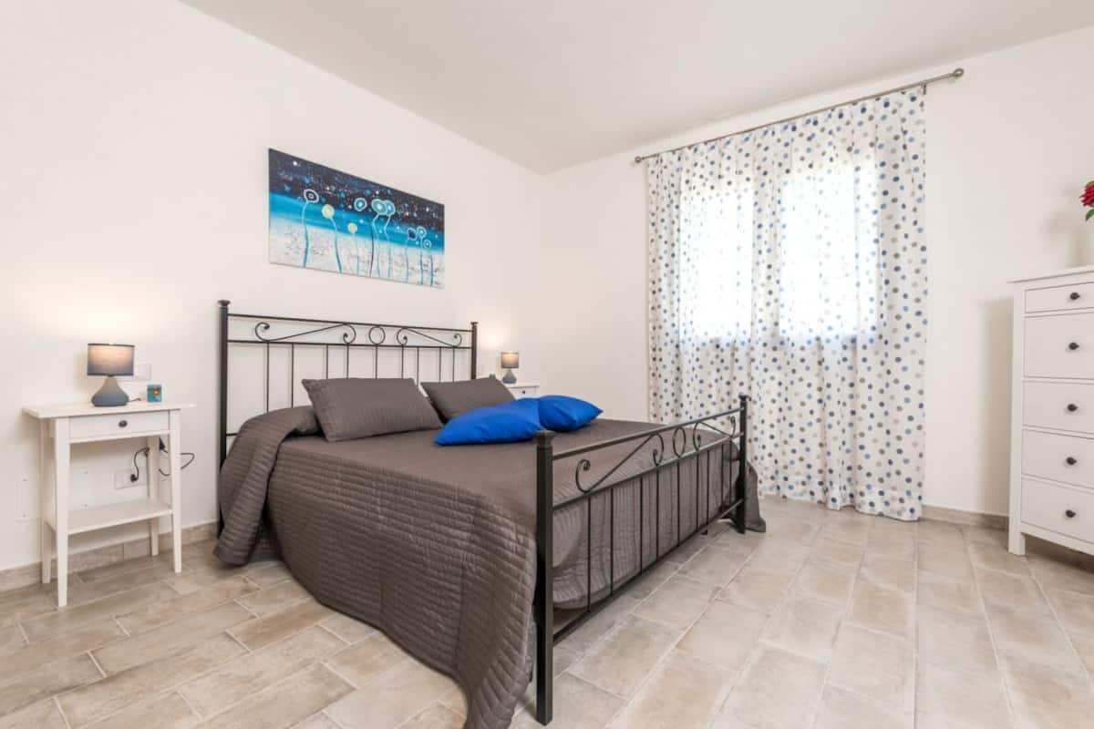 Ein Schlafzimmer mit Bett, Nachttisch, Kommode und einem Bild an der Wand.