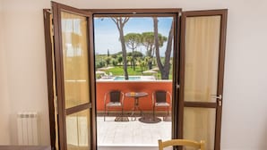 A room with a sliding glass door leading to an outdoor area with a pool, chairs, and a table. - Agriturismo Nonno Gino - Charme&Relax (Piombino)