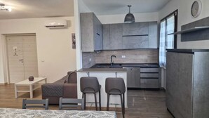 A compact kitchen with modern appliances, a dining area with a table and chairs, and a small seating area with a sofa and cushions. - Agriturismo Nonno Gino - Charme&Relax (Piombino)