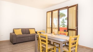 A dining area with a table and chairs, a sofa, and a sliding glass door leading to an outdoor area. - Agriturismo Nonno Gino - Charme&Relax (Piombino)
