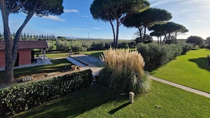 A well-maintained garden with a patio area, large trees, and a clear sky. - Agriturismo Nonno Gino - Charme&Relax (Piombino)