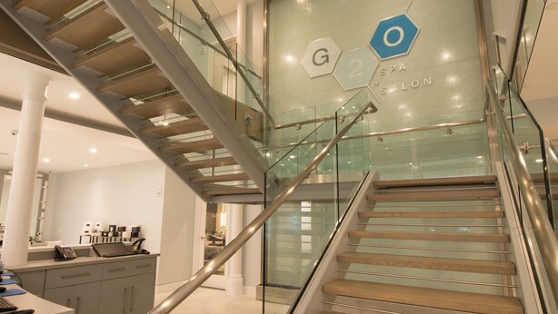 A modern interior with a glass staircase leading to a spa salon. - Exclusive One Bedroom Suite (Boston)