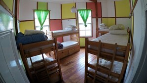 Un dormitorio con literas, pisos de madera y una ventana con cortinas verdes.
