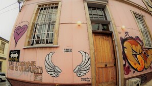 Un edificio rosa con grafitis, una puerta de madera y ventanas con barrotes.