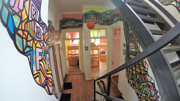 Una escalera con un mural colorido en las paredes que lleva a una habitación con literas.