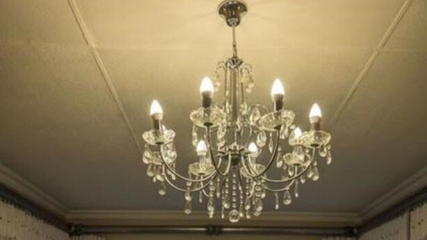 A room with a large window overlooking the sea, a chandelier, and two massage tables. - Island Cottage Guesthouse (Luderitz)