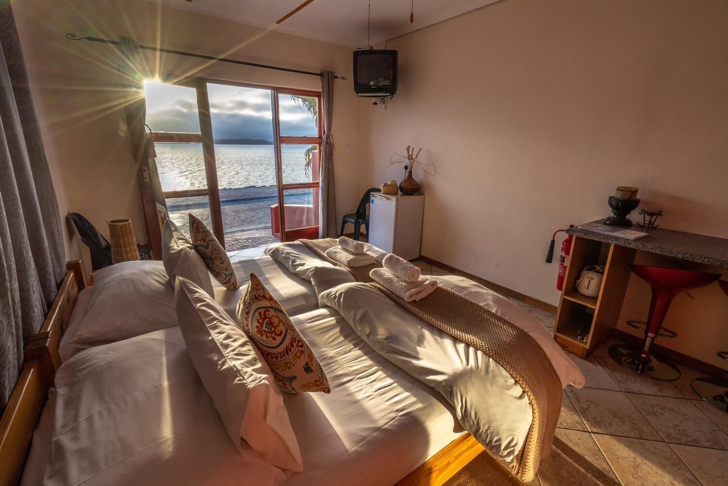 Une chambre avec un lit, un bureau, une chaise, une télévision et une vue sur la mer.
