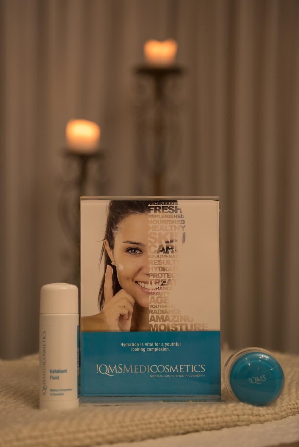 A box of Qomsmedicosmetics with a blue label and a white tube beside it.