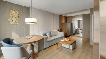 A modern living room with a round wooden table, a grey sofa, and a blue armchair.
