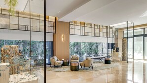 A spacious lobby with a high ceiling, modern furniture, and large windows offering views of greenery. - DoubleTree by Hilton Taipei Zhongshan (Taipei)