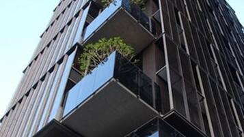 Un edificio moderno con varios balcones, algunos con plantas.