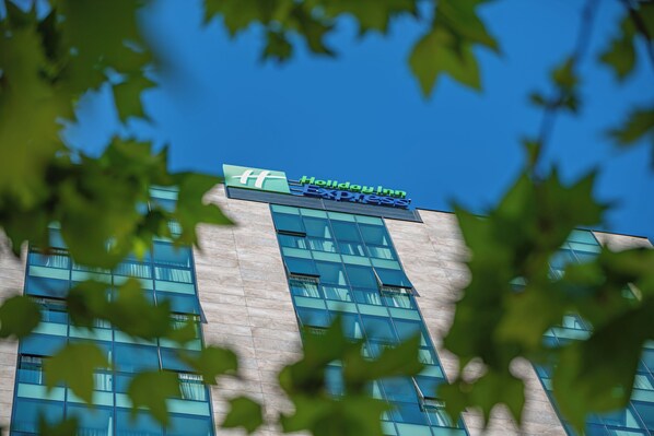 A Holiday Inn Express hotel with a modern glass facade and a clear blue sky in the background.