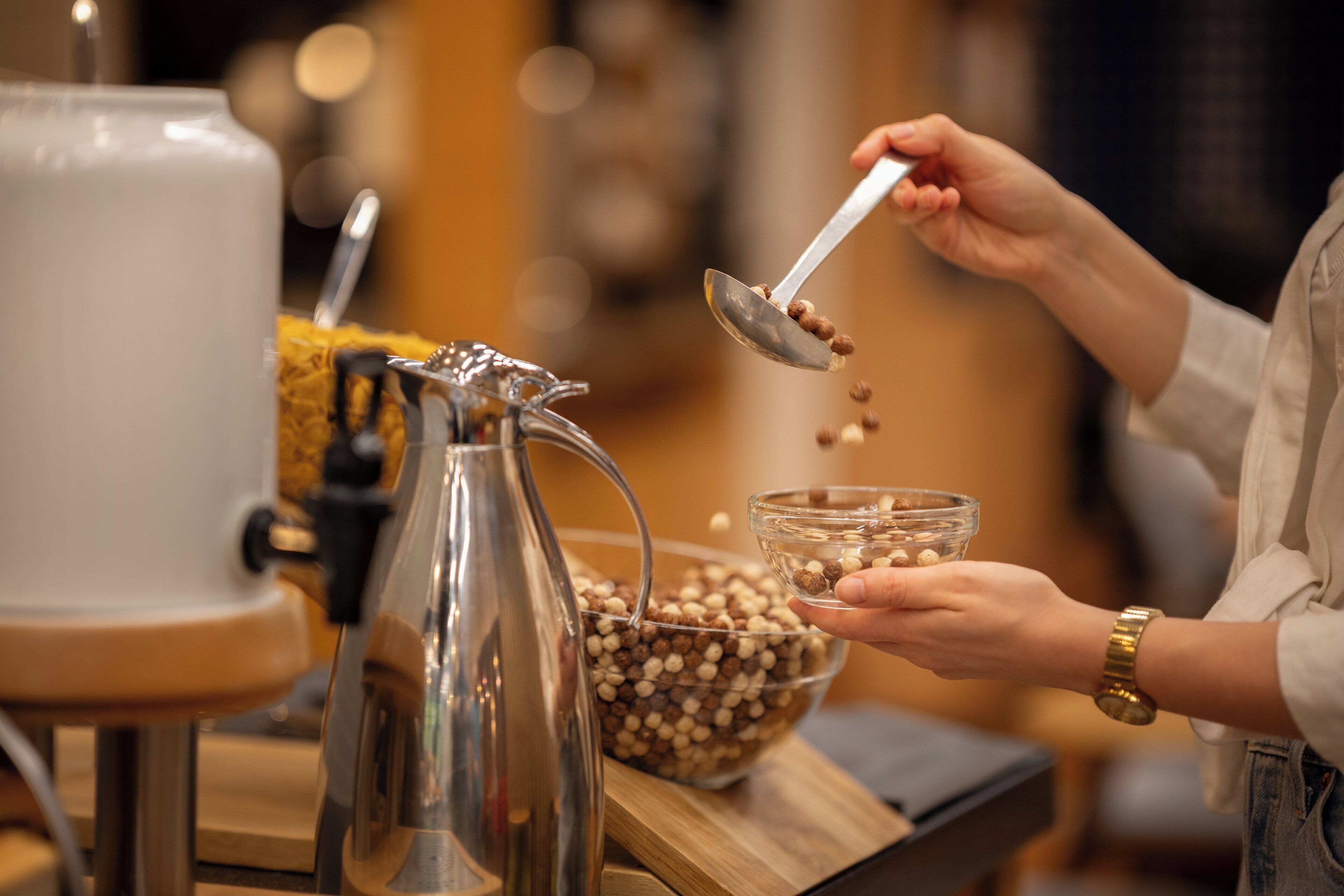 A person pouring coffee beans into a glass bowl.