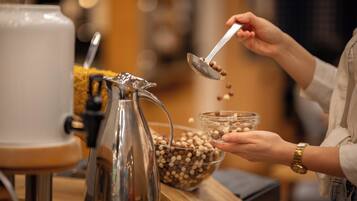 A person pouring coffee beans into a glass bowl.