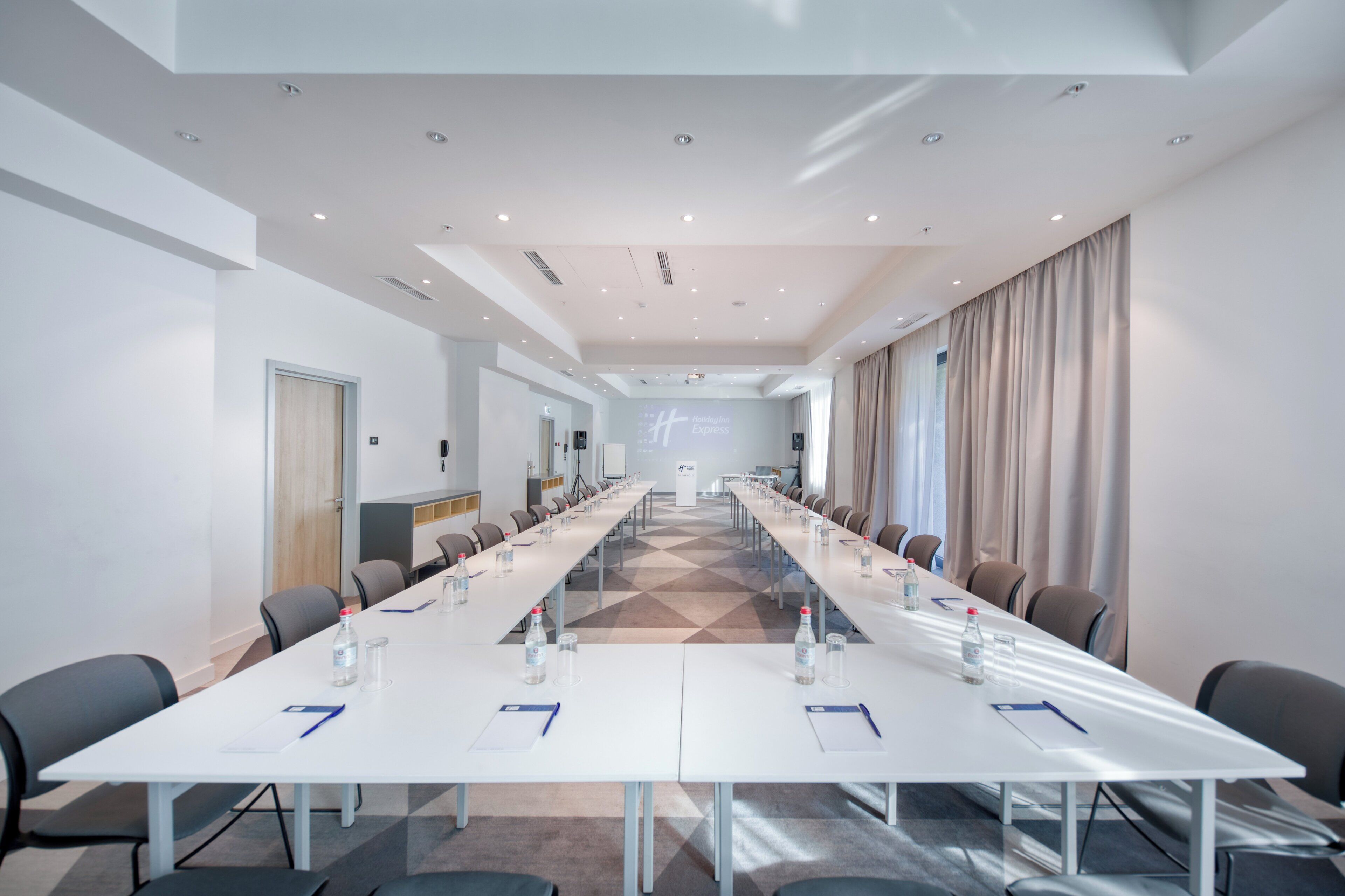 A conference room with a long table, chairs, and a projection screen.