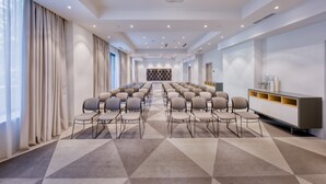 Sala de conferências com fileiras de cadeiras, um projetor e uma tela grande.