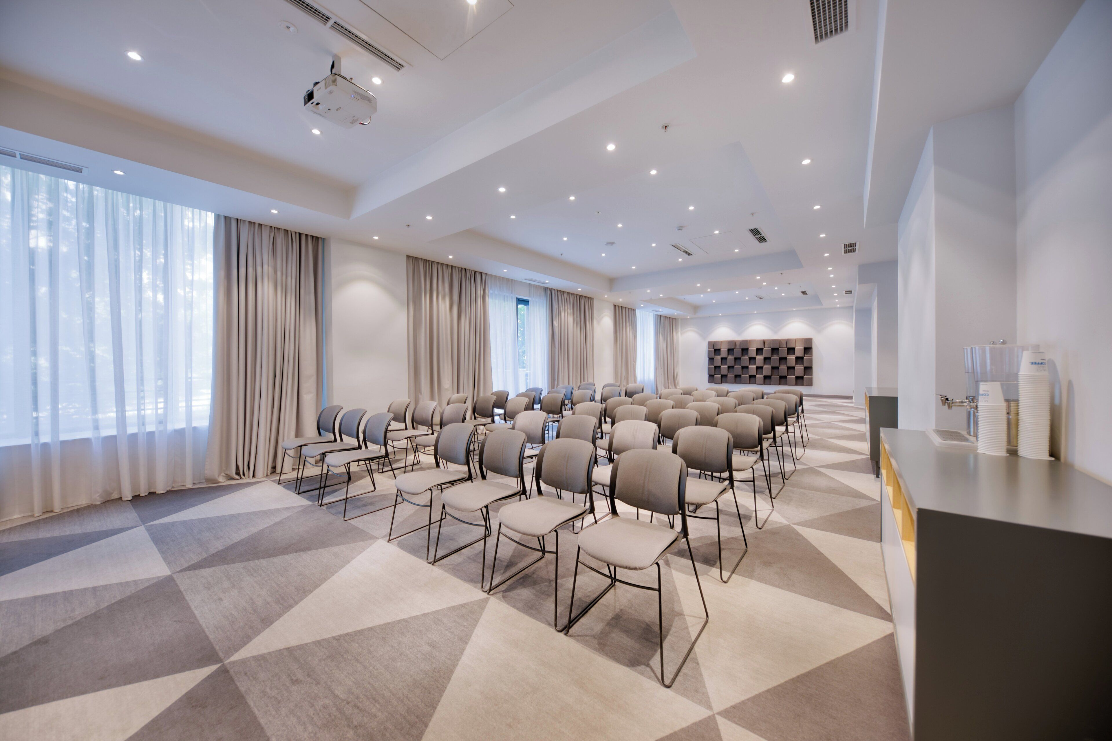 A conference room with rows of chairs, a projector, and a coffee station.