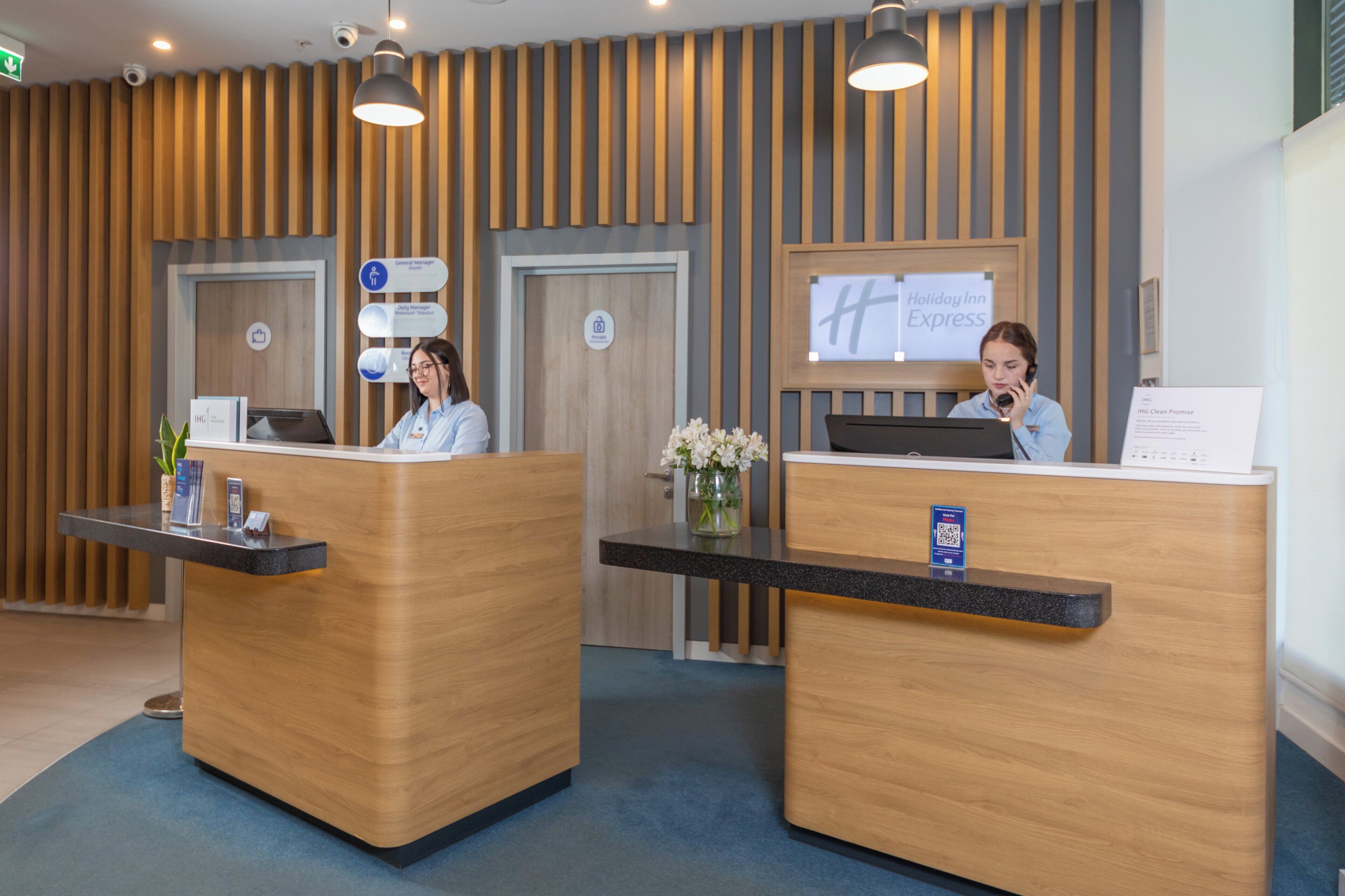 A reception desk with two receptionists, a sign for Holiday Inn Express, and a private room indicator.