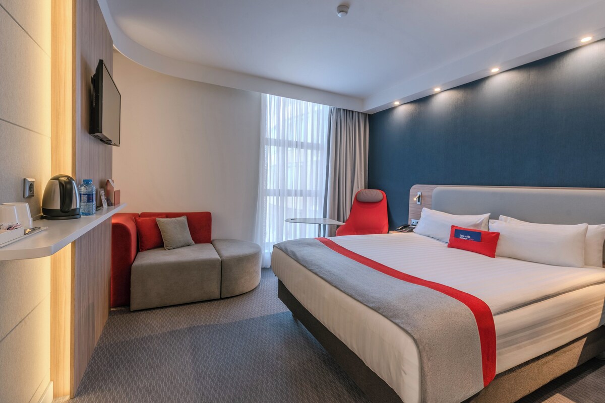 Una habitación de hotel con cama, sofá, escritorio, silla y ventana.