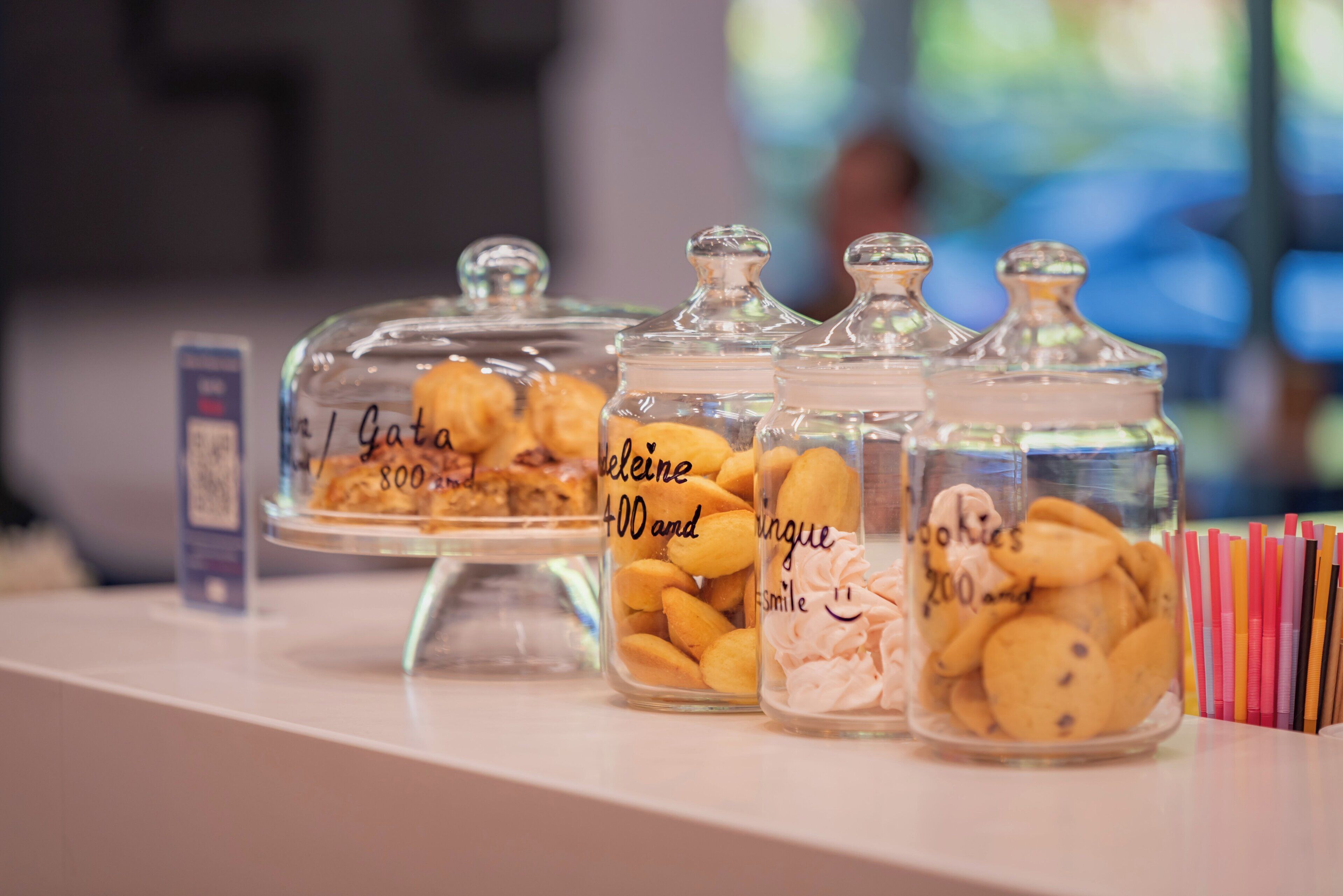 A display of various baked goods in glass jars with labels, placed on a counter.