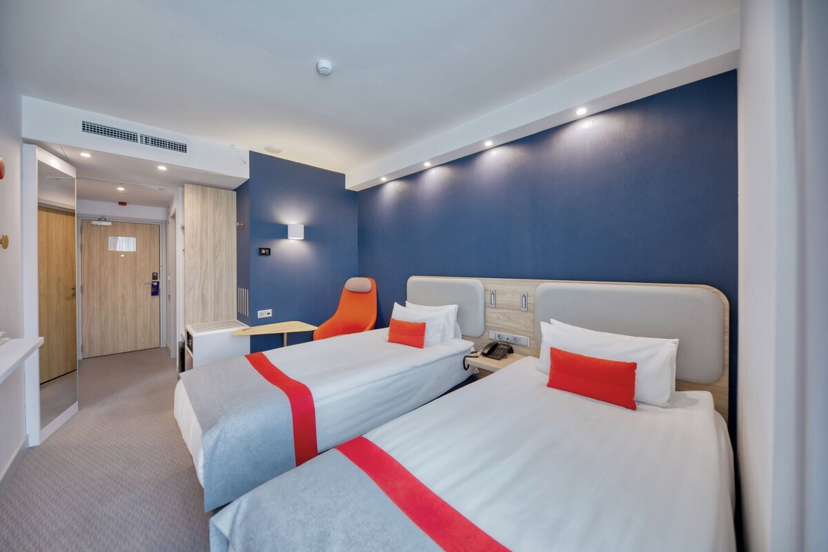 Habitación de hotel con dos camas, un escritorio y una silla.
