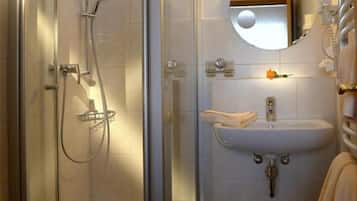 Un baño moderno con cabina de ducha de vidrio, un lavamanos con espejo y un perchero para toallas.