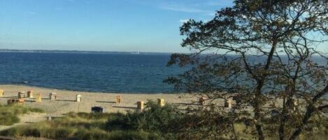 A beach with a clear view of the sea and distant land. There are some structures on the beach, possibly for beachgoers.
