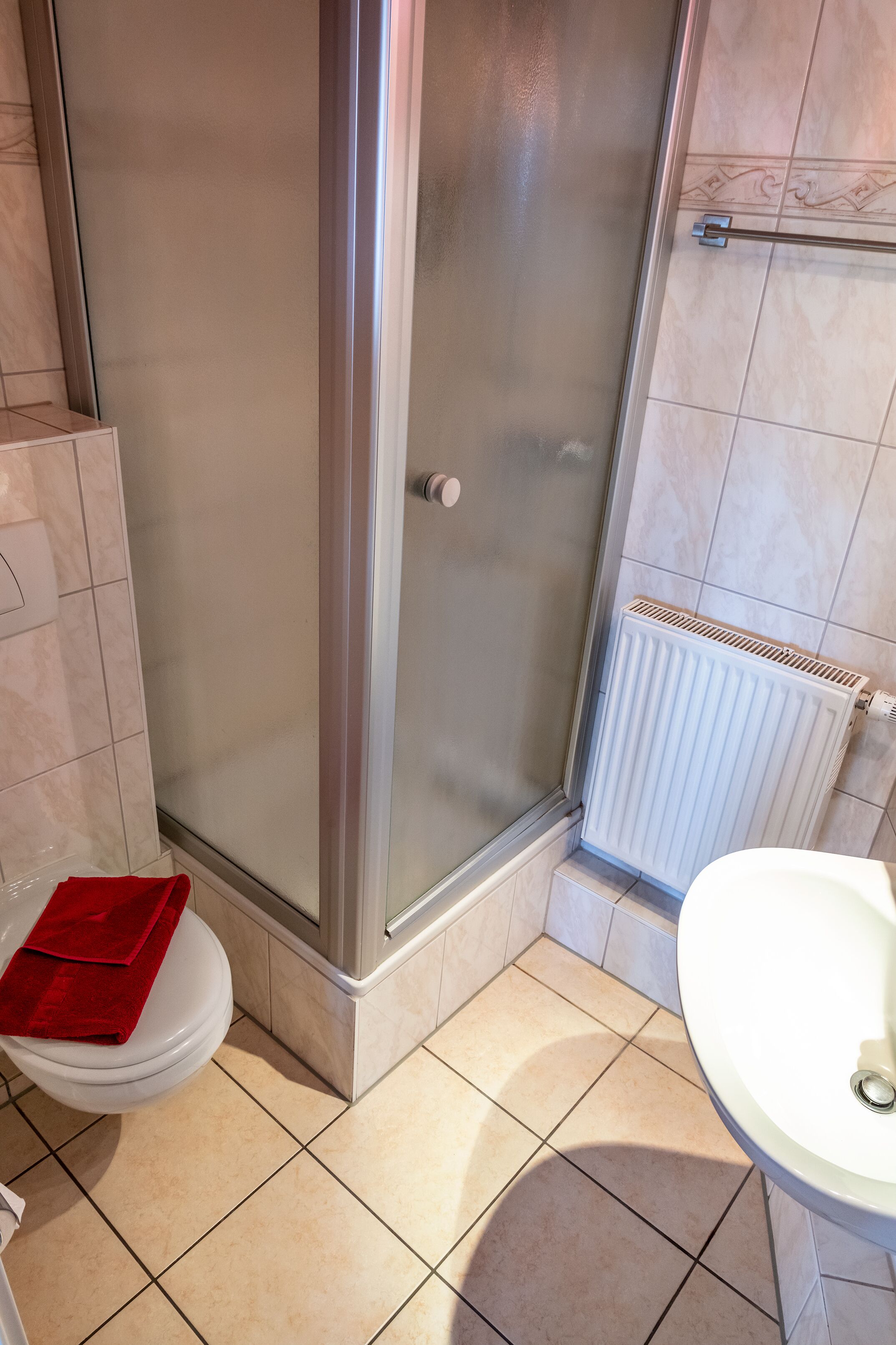 A bathroom with a glass shower enclosure, a white toilet, and a white sink.
