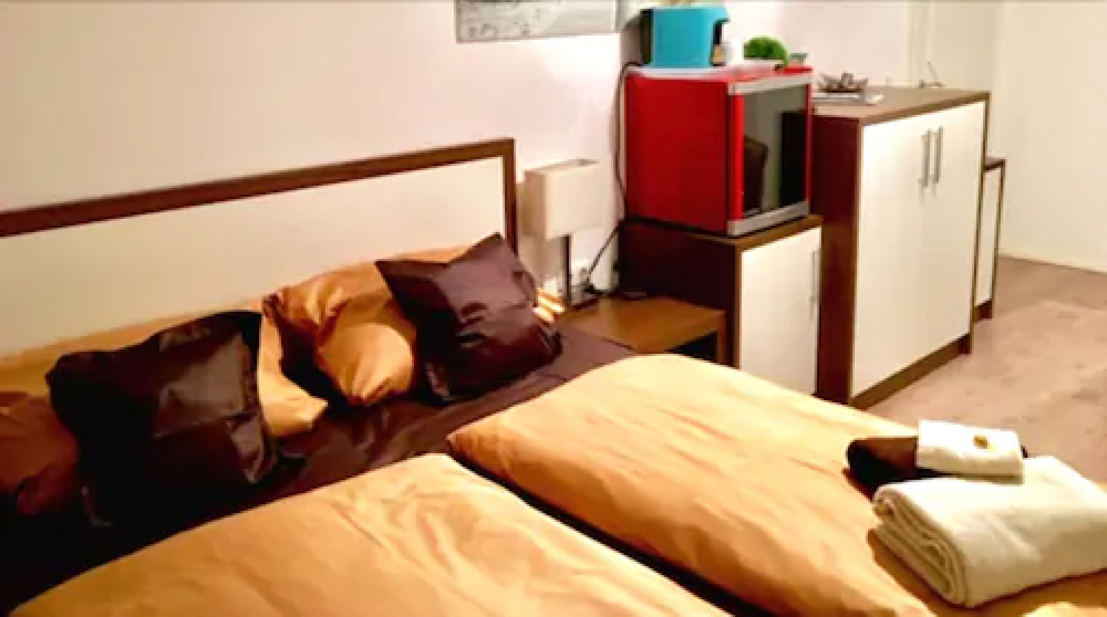 Une chambre d’hôtel avec deux lits, une télévision, une armoire rouge et une petite table.