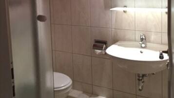 Une salle de bain avec des toilettes, un lavabo et une douche.