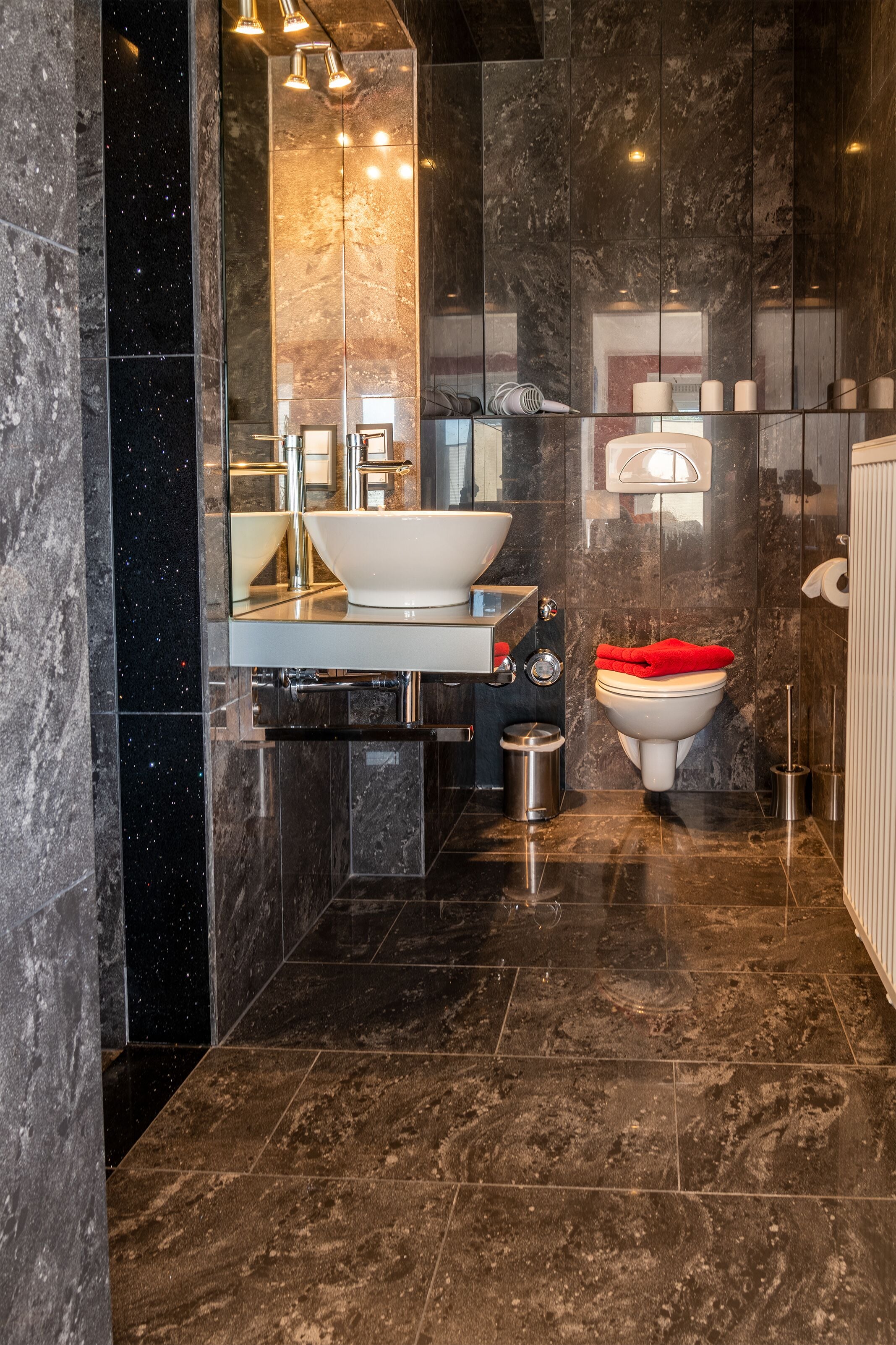 Une salle de bain moderne avec un grand miroir, un lavabo blanc et des toilettes.