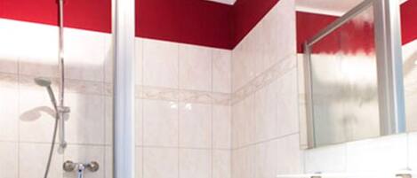 A bathroom with a shower, a sink, and a red towel.